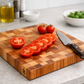Stirnholz-Schneidbrett aus Vollholz mit aufgeschnittenen Tomaten und Messer auf einer Küchenzeile