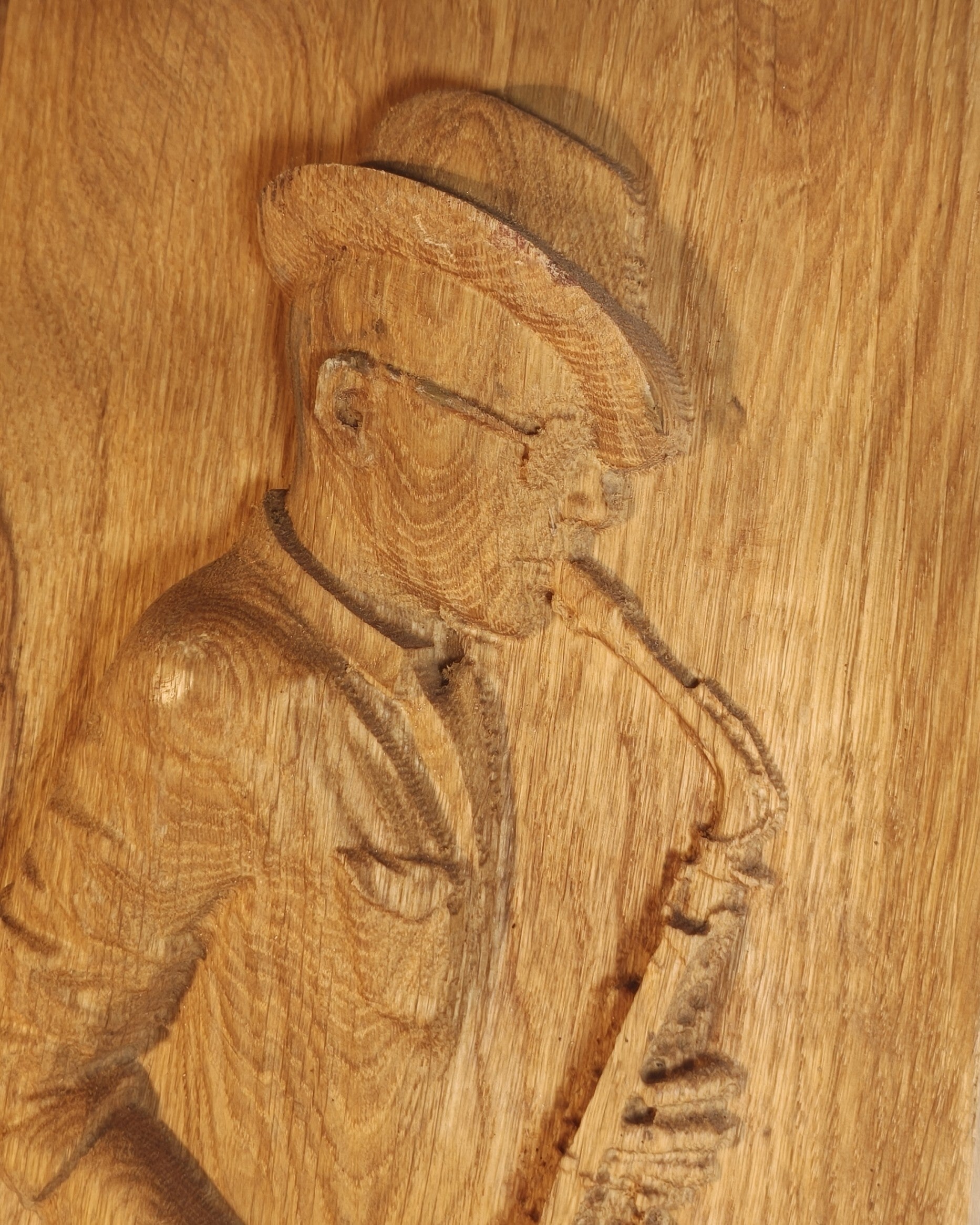 Detailaufnahme einer Schnitzerei eines rechteckigen Holzbildes, das einen Saxophonisten zeigt